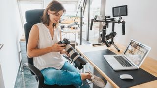 Smiling female professionalphotographer checking camera sitting on a chair in a photo studio