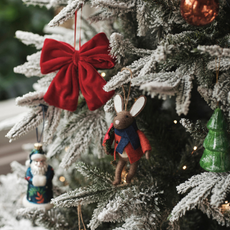 Felt mouse decoartion on frossted Christmas tree with a red bow and green tree ornament