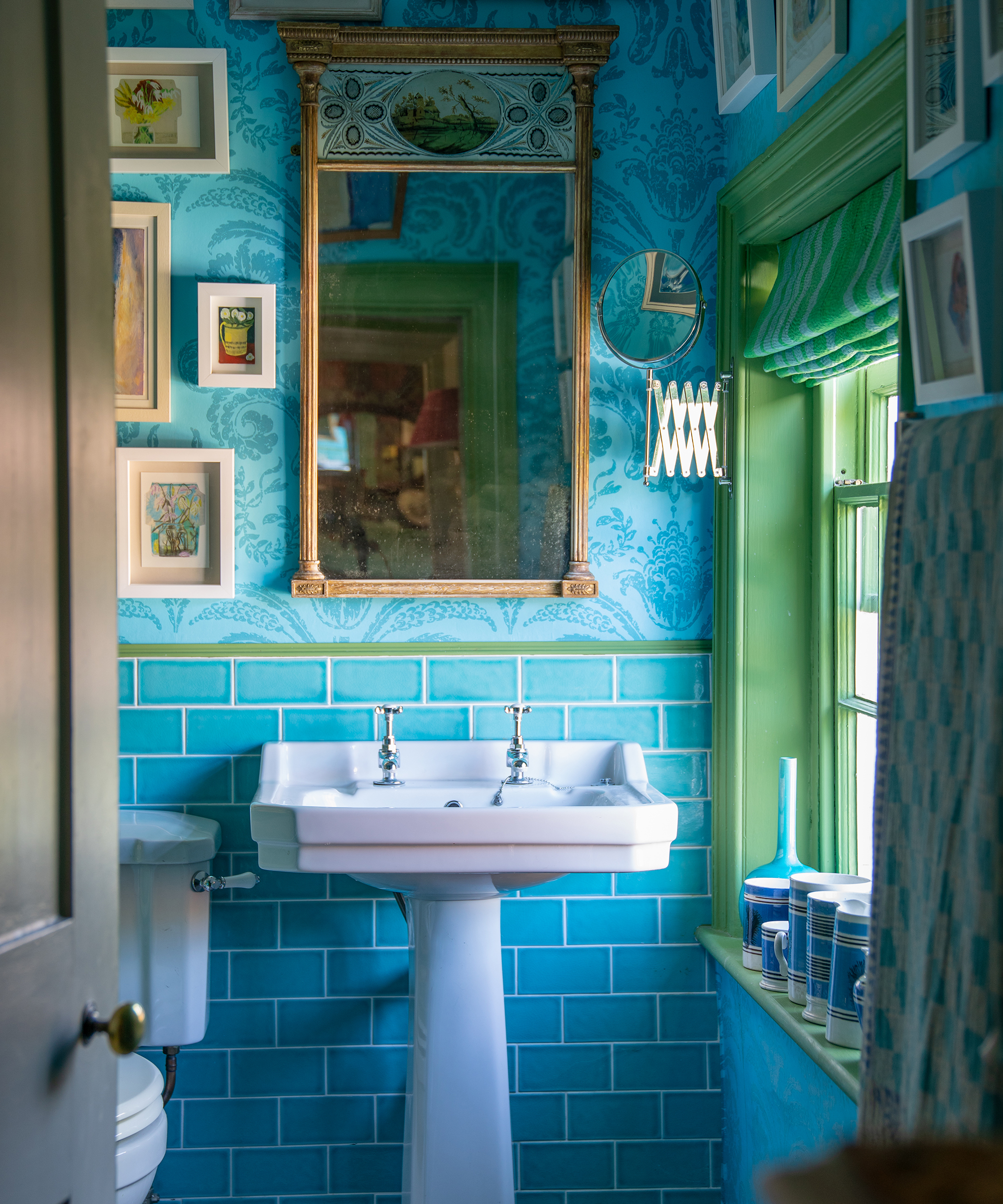 Blue and green traditional style bathroom with wall art and antique mirror