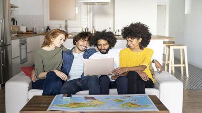 Four friends on a couch plan a vacation using travel sites.