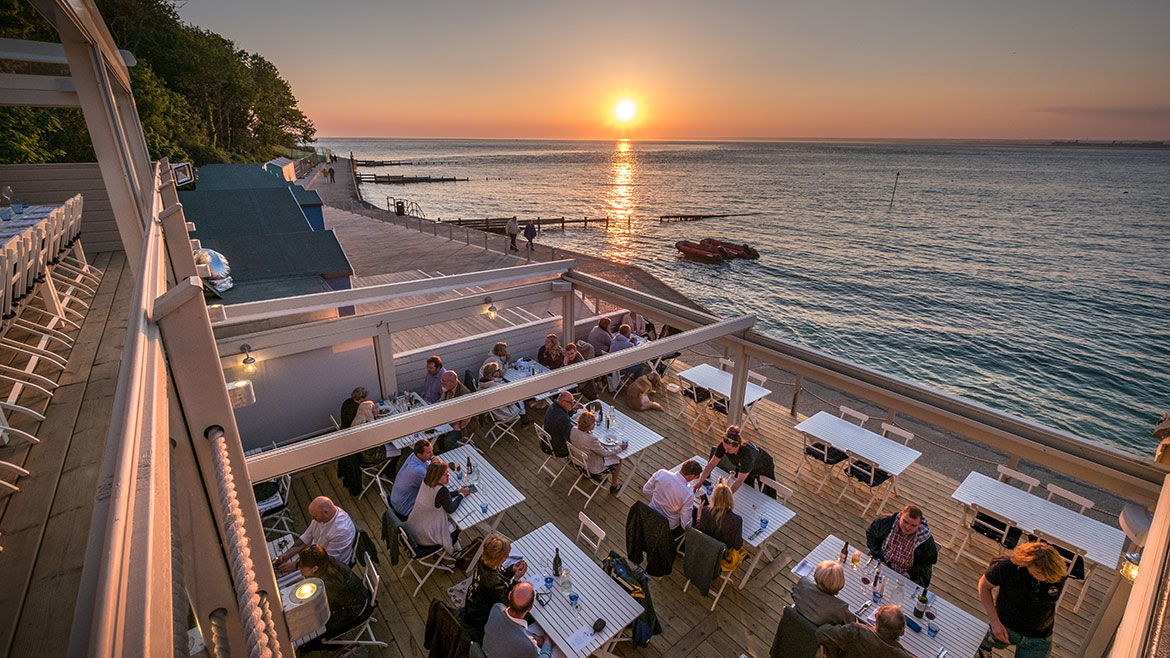 Diners eating outside at sunset at The Hut, Colwell Bay