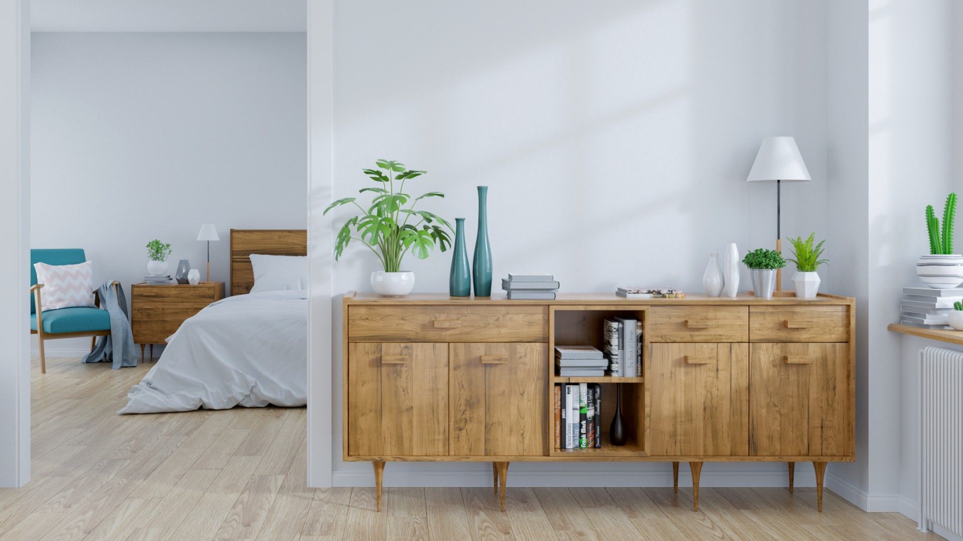 a wooden cabinet in a room with a bedroom just beyond, with a bed and a blue armchair