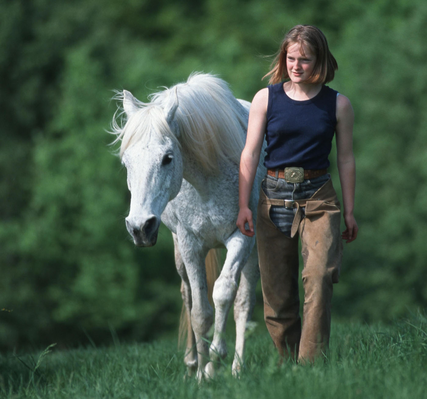 Woman walking alongside grey horse at liberty
