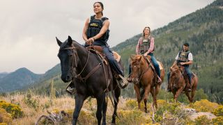 Pictured (L-R): Ash Santos as Andrea and Arielle Kebbel as Belle riding horses in a line.