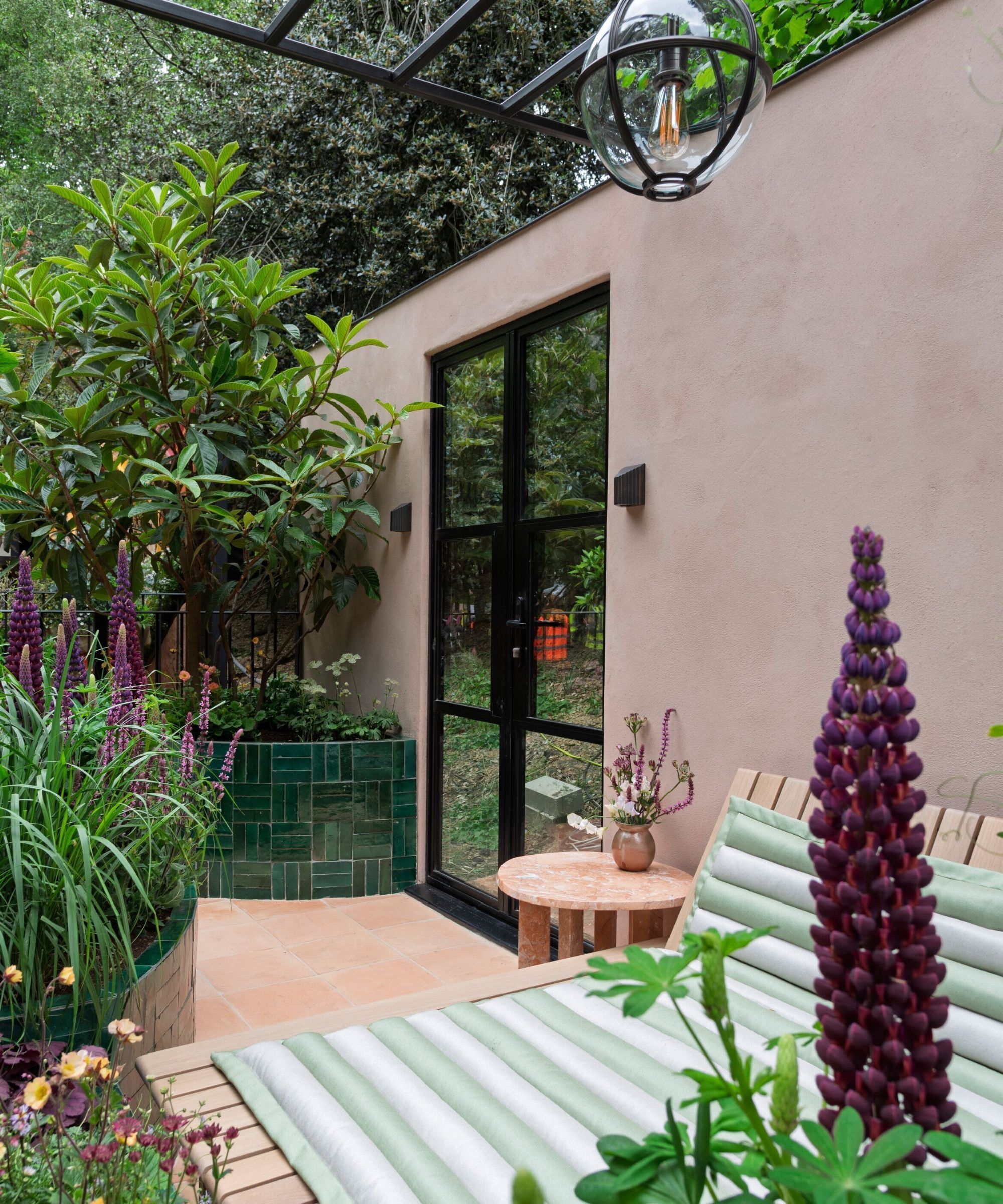 A simple city balcony garden planted with flowers, shrubs and trees