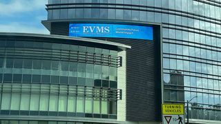 A large, curved LED Daktronics display reads EVMS outside the school building draped in windows. 