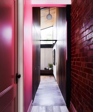 dark pink painted hallway, pink brickwork, wooden flooring, rounded white hanging pendant