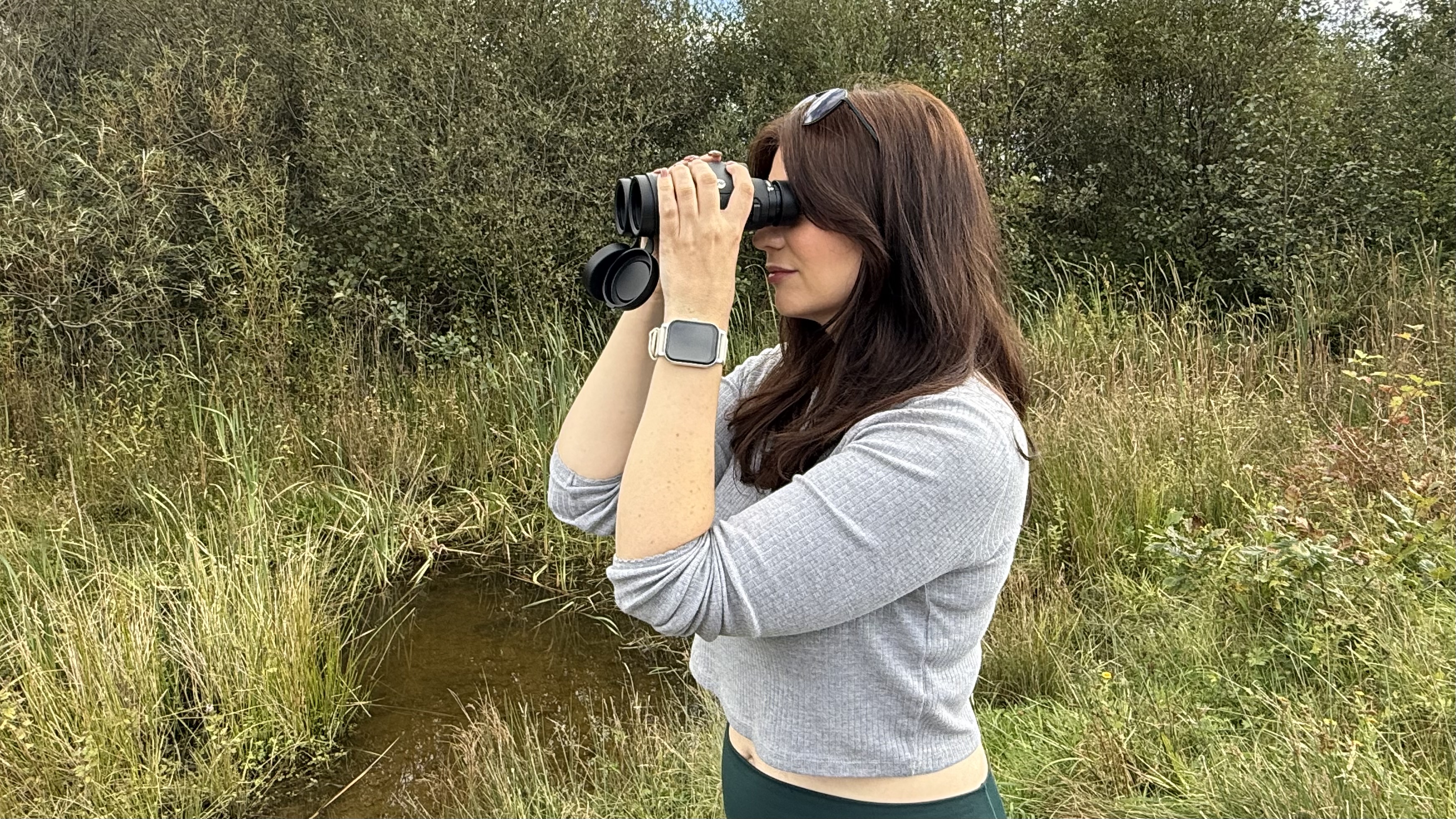 woman using the Celestron Nature DX ED 10x42 binoculars in a nature reserve