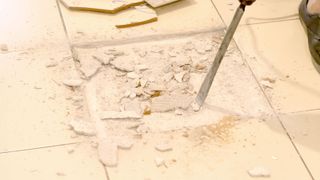 Powered chisel breaking beige floor tile