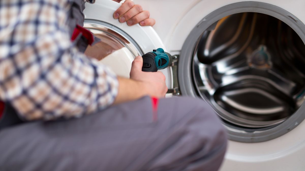 Man installing a dryer door with a screwdriver.