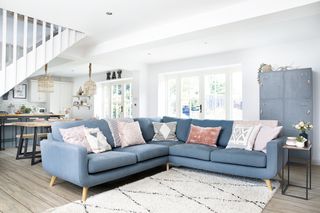 Living area of an open-plan space with blue sofa, wood flooring, black and white rug and blue metal locker