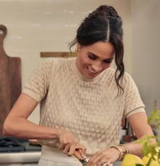 Meghan Markle cutting fruit on a kitchen table in her show With Love, Meghan