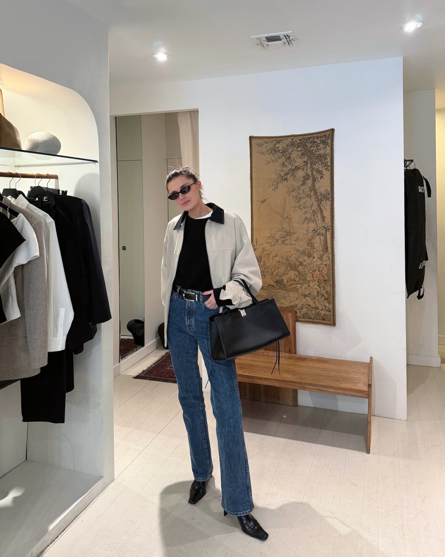 @cocoschiffer wearing a tan jacket, black top, cigarette jeans, and black pointed toe boots.