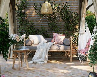 A Mediterranean patio area with herringbone patterned tiles and a gray outdoor sofa