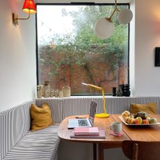 Banquette seating with striped cushions and an retro table with a yellow task lamp and laptop