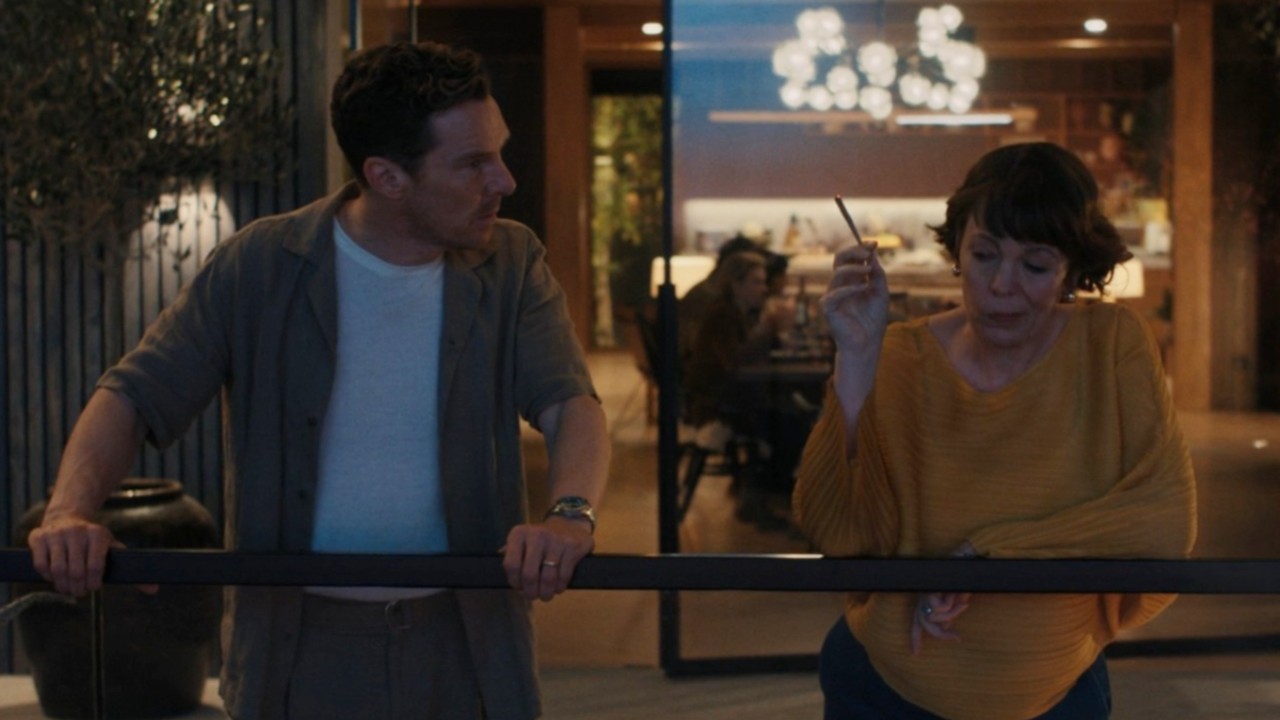 Olivia Colman and Benedict Cumberbatch standing on a balcony on The Roses.