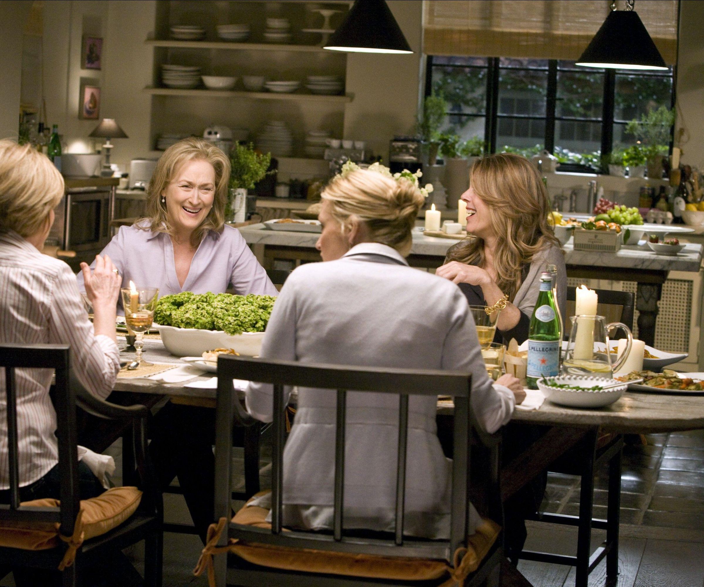 actresses including Meryl Streep sat in the kitchen around a dining table in the movie It's Complicated with her kitchen shown behind
