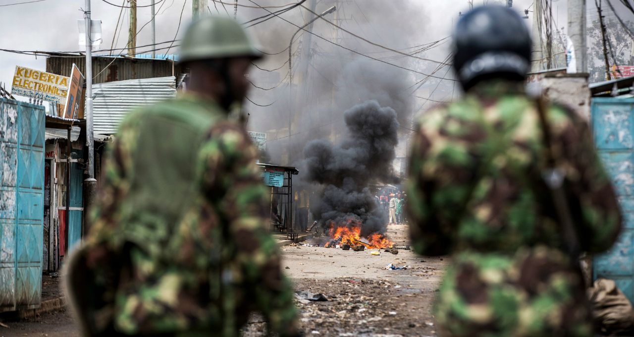 Nairobi police check a street with a burning barricade as protesters try to block access to a polling station.