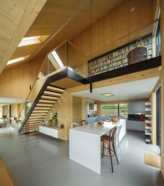 timber clad open plan kitchen and dining space with vaulted ceiling and mezzanine