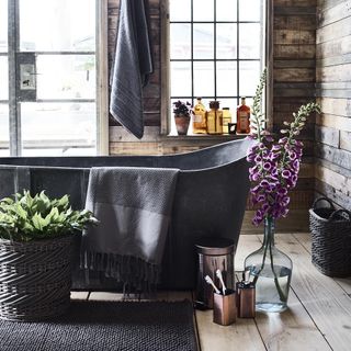 bathroom with bathtub and wooden wall and wooden floor and towel
