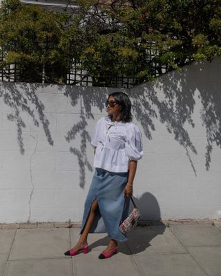 Woman on street wears white blouse, denim maxi skirt, pink shoes