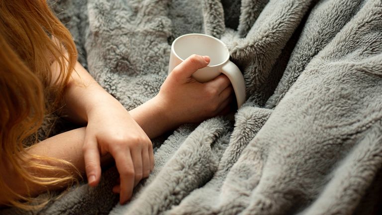 Person under a blanket with mug of drink