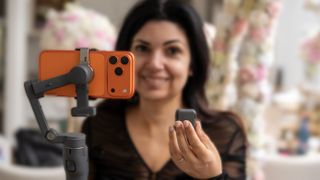 DJI Osmo Mobile 8P with gimbal in one hand and remote in other as being held by Ariane Sherine Juniper