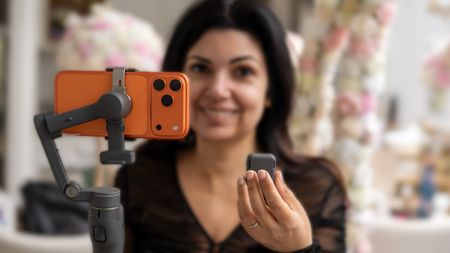 DJI Osmo Mobile 8P with gimbal in one hand and remote in other as being held by Ariane Sherine Juniper