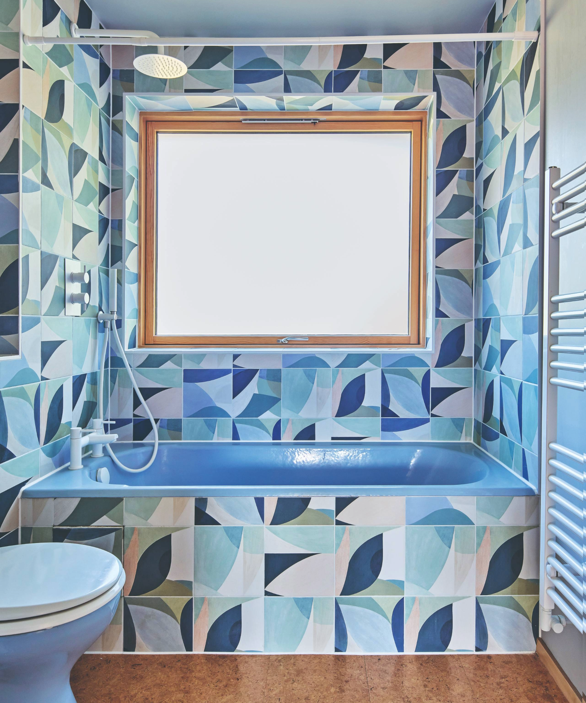 Bathroom with blue patterned wallpaper and blue bath and toilet