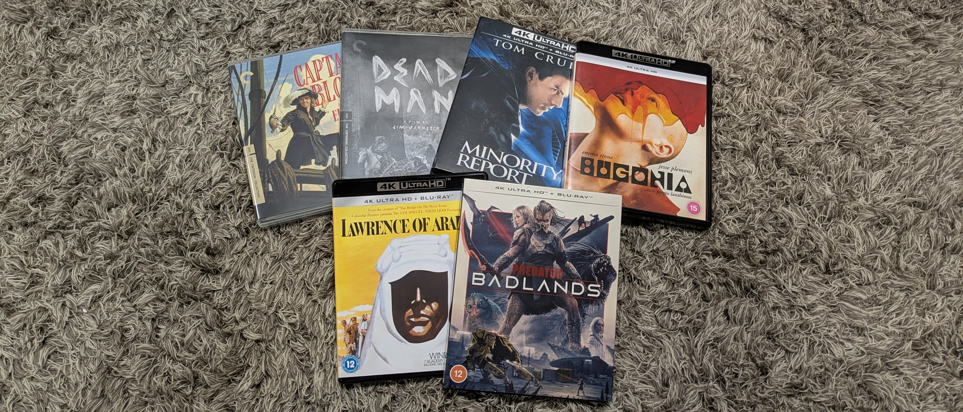 4K Blu-ray collection hero image with Minority Report, Lawrence of Arabia, Bugonia, Predator: Badlands, Dead Man and Captain Blood 4K Blu-ray cases on a carpet