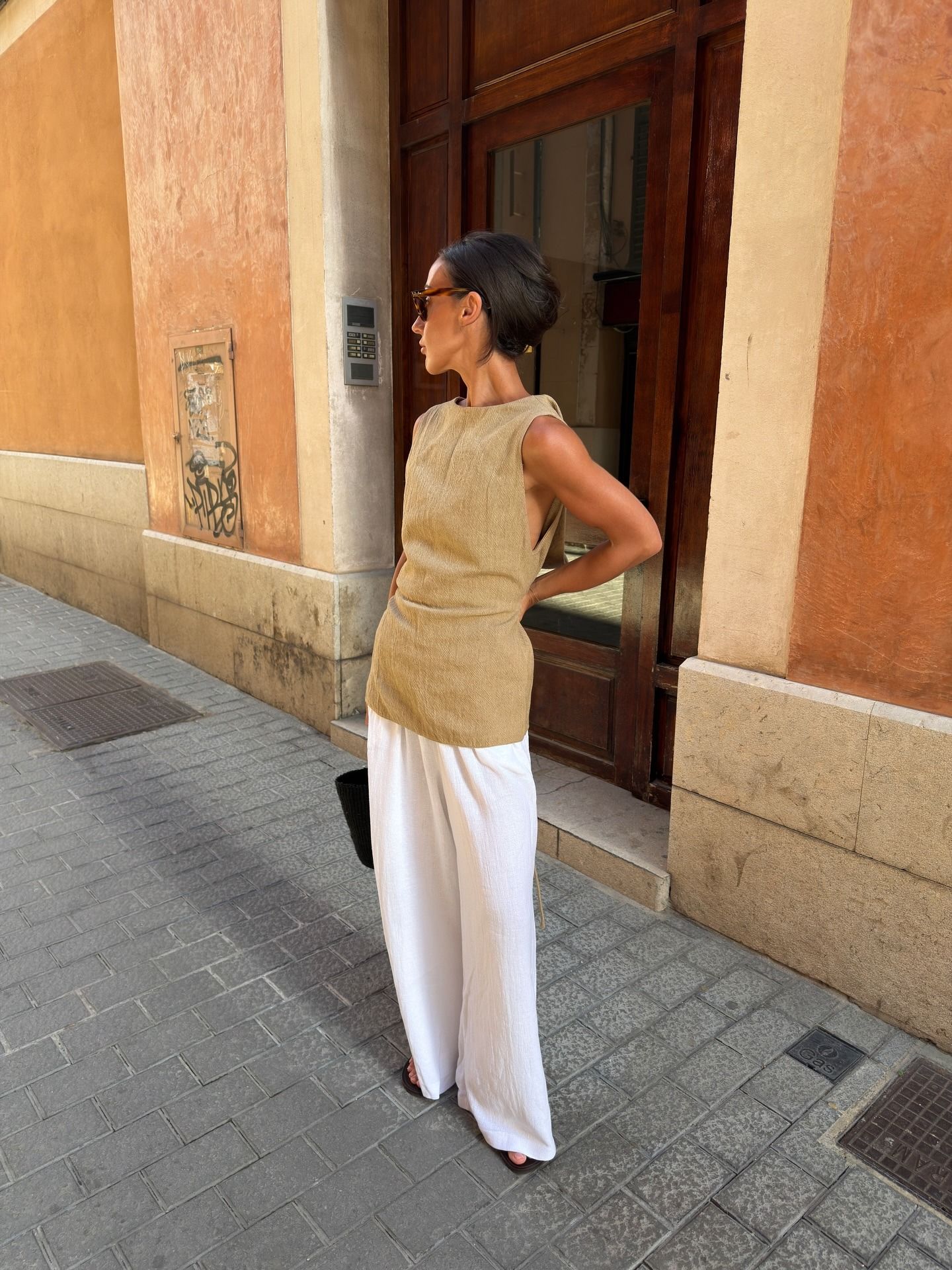 em wears a tan top and white pants.