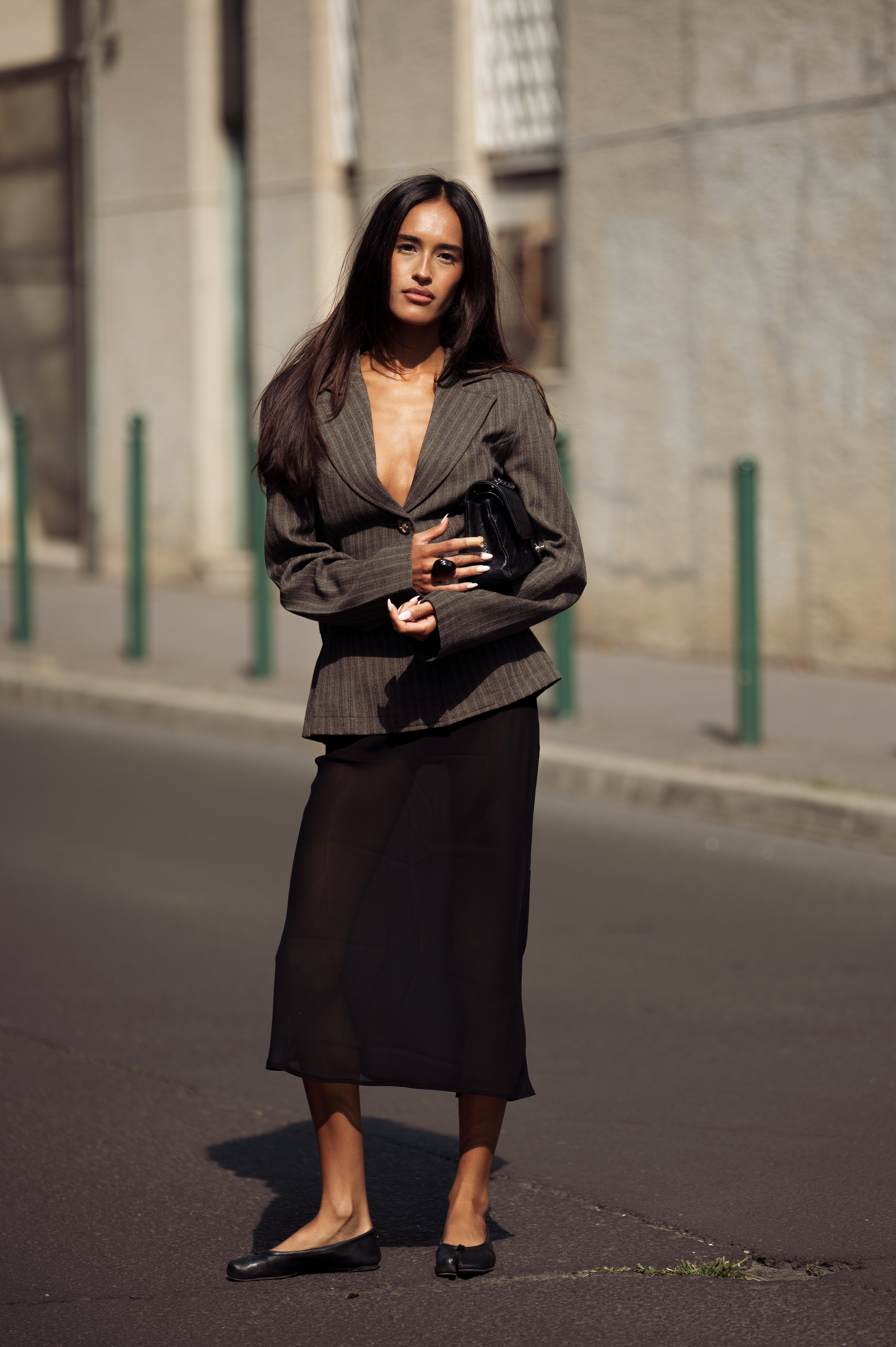 a woman wearing a sculpted blazer and midi skirt during fashion week