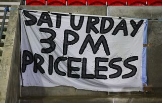 A banner reading 'Saturday 3pm priceless' hangs on the stand prior to the Emirates FA Cup first round match between FC United of Manchester and Chesterfield at Broadhurst Park on November 9, 2015 in Manchester, England. Some FCUM fans were unhappy at the moving of the fixture to a Monday evening.