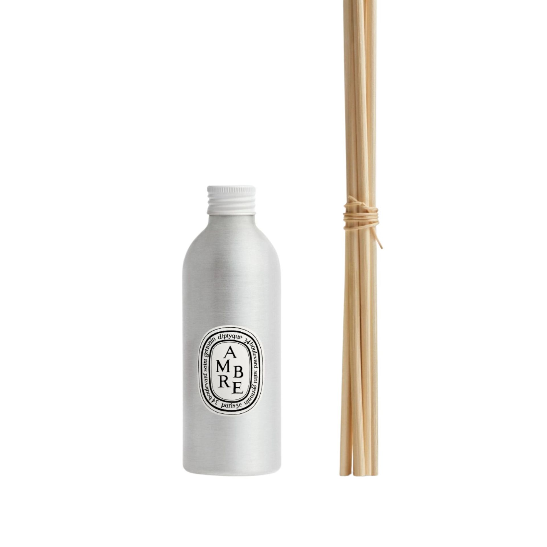 Diptyque Ambre refill scent in a silver bottle and brown wooden reeds