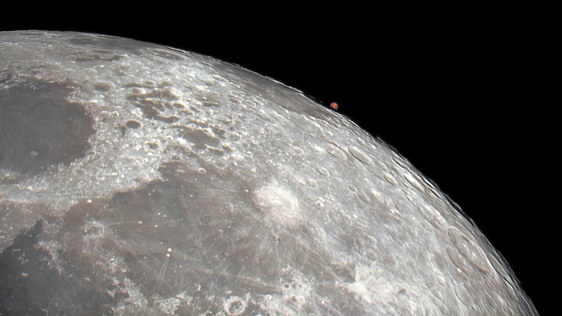 a photograph of Mars rising behind the moon
