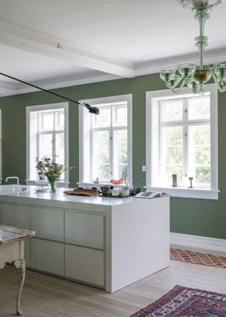 green and white kitchen with white modern kitchen island and green wall