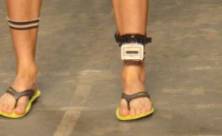Someone wearing flip-flops and a device around one ankle