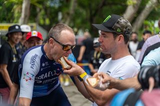 Chris Froome (Israel Premier Tech and TDF Legends team) is fed an ice-cream sandwich by the retiring Mark Cavendish (Astana-Qazaqstan) at the Tour de France Prudential Singapore Criterium