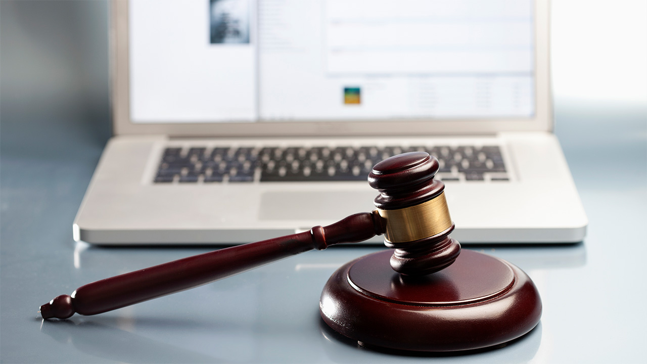 Brown gavel resting in front of silver laptop