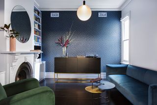 A living room with a blue wallpaper and a navy blue sofa