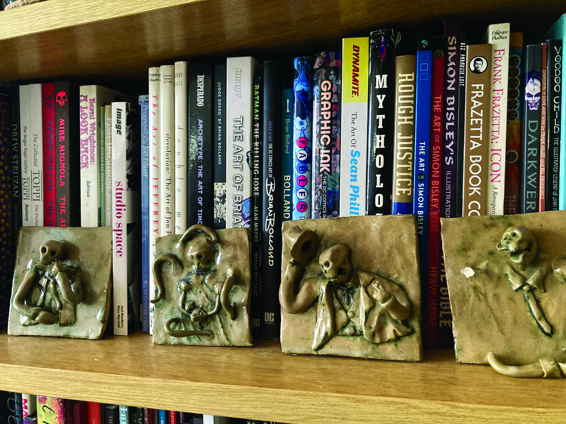 Artist in residence; ceramic tiles showing skeletal figures on a bookcase