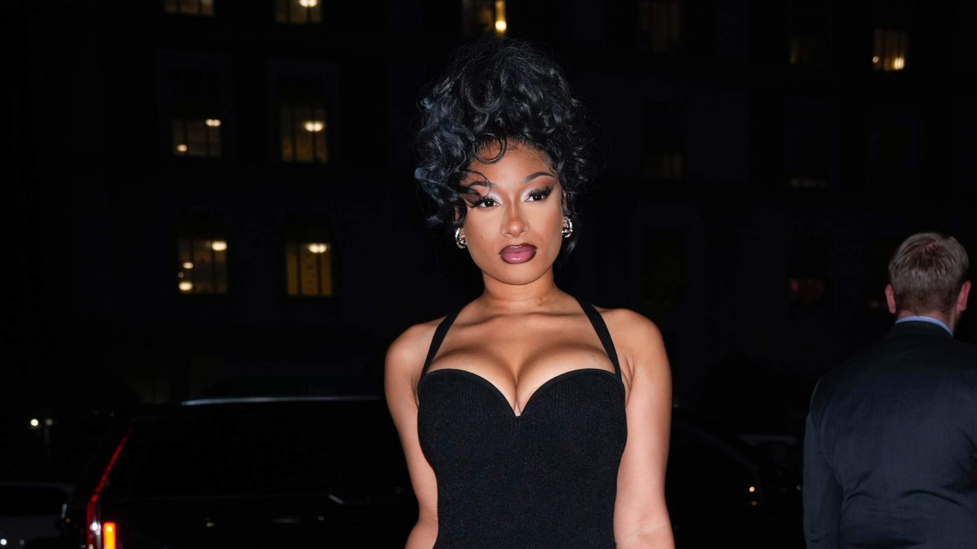 Megan Thee Stallion wearing a black dress and curly updo hairstyle.