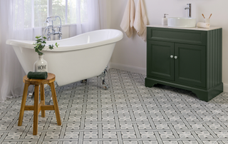 Bathroom with patterned tiled flooring, green under sink cabinet and freestanding bath