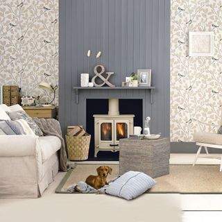 Living room with grey wood panelling, woodburning stove, bird wallpaper and neutral furnishings
