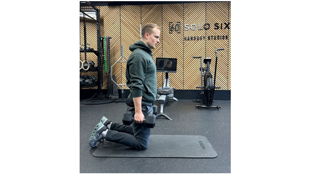 Ollie Thompson starting a tall-kneeling biceps curl and press