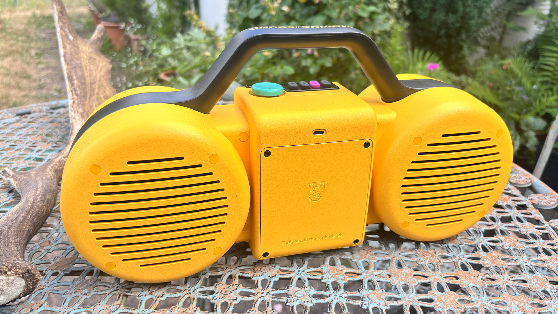 Philips The Roller wireless speaker on metal garden table showing rear speaker grilles