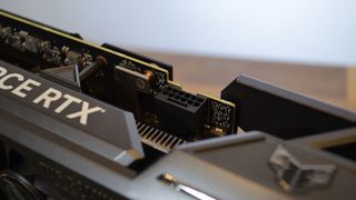 Una tarjeta gráfica Nvidia GeForce RTX 4070 Ti sobre una mesa de madera con su embalaje de venta al público.