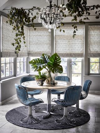 sun room with silver blinds and modern chairs around a circular table on a rug