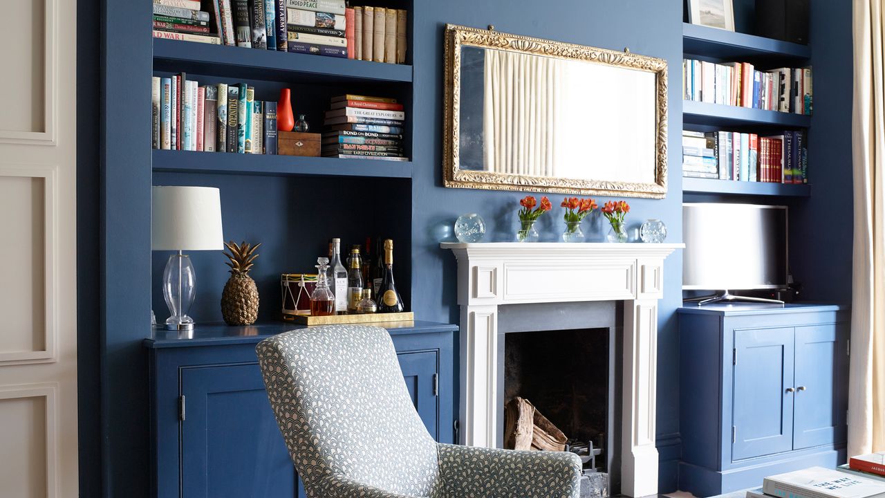 blue living room with gilt mirror above fireplace