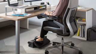 A person using a footrest at their desk